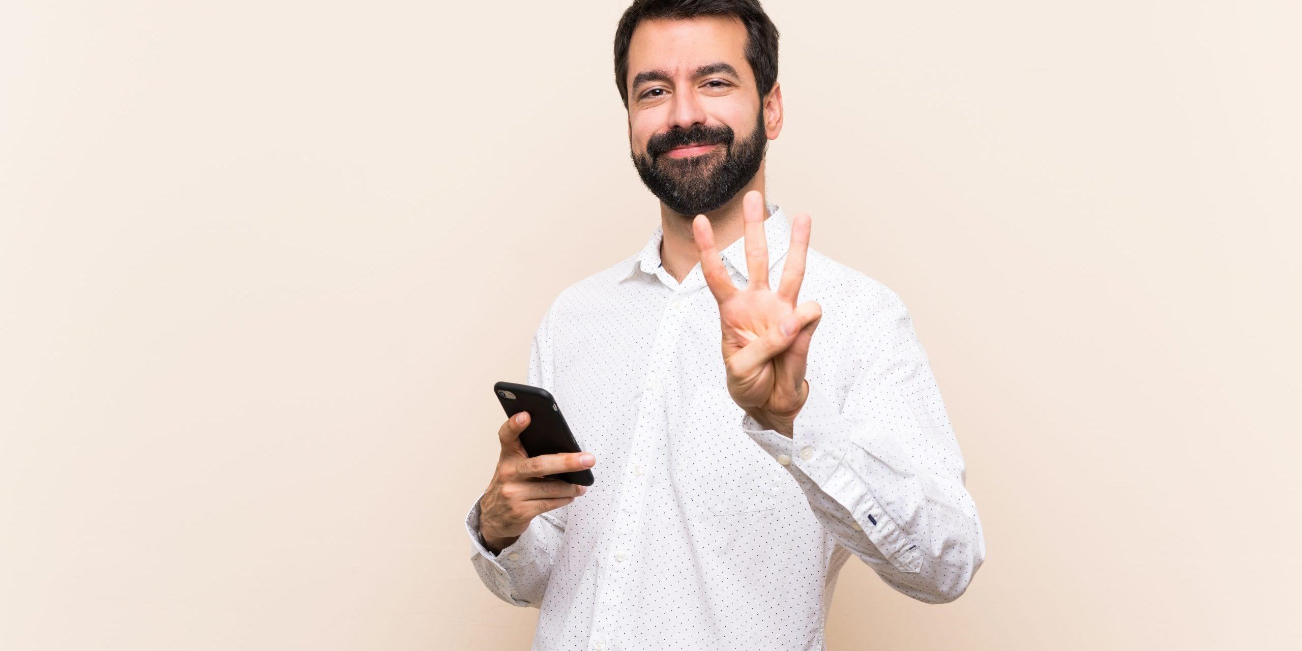 Young,Man,With,Beard,Holding,A,Mobile,Happy,And,Counting